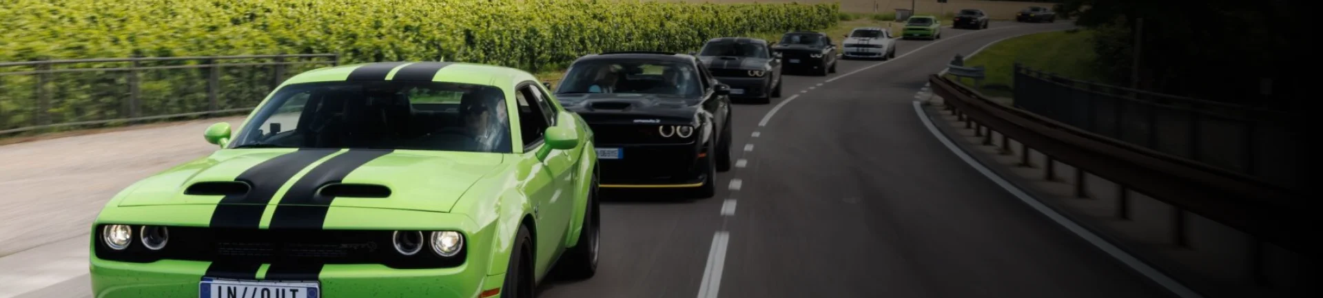 Dodge charger and several black cars behind it on a highway