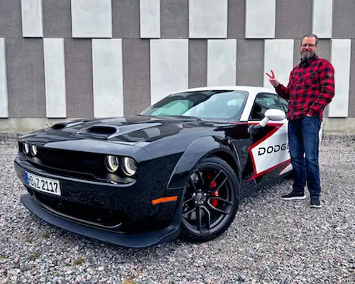 Sneaky Pete standing next to a muscle car